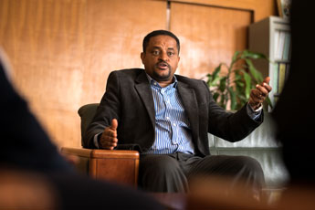 Seated man speaking in an office setting.