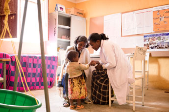 Clinician interacts with child during pediatric medical visit.